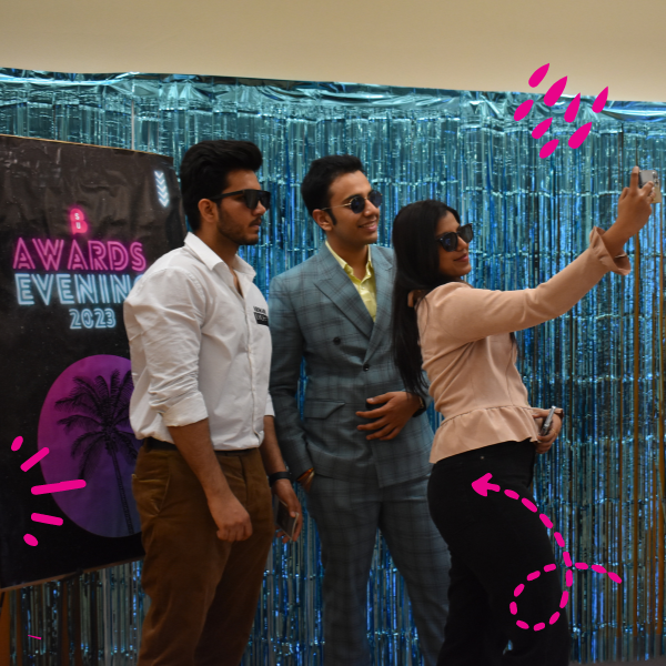 Students taking a selfie wearing sunglasses with a glittery blue background