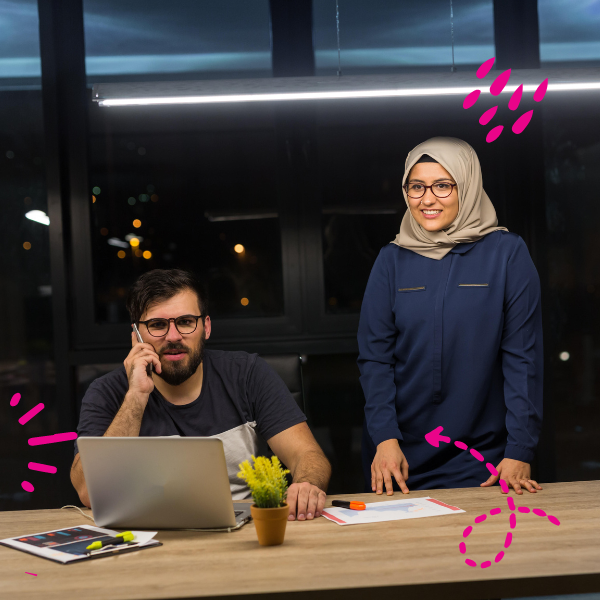 Photo of a student on the phone and on their computer and an other student looking up